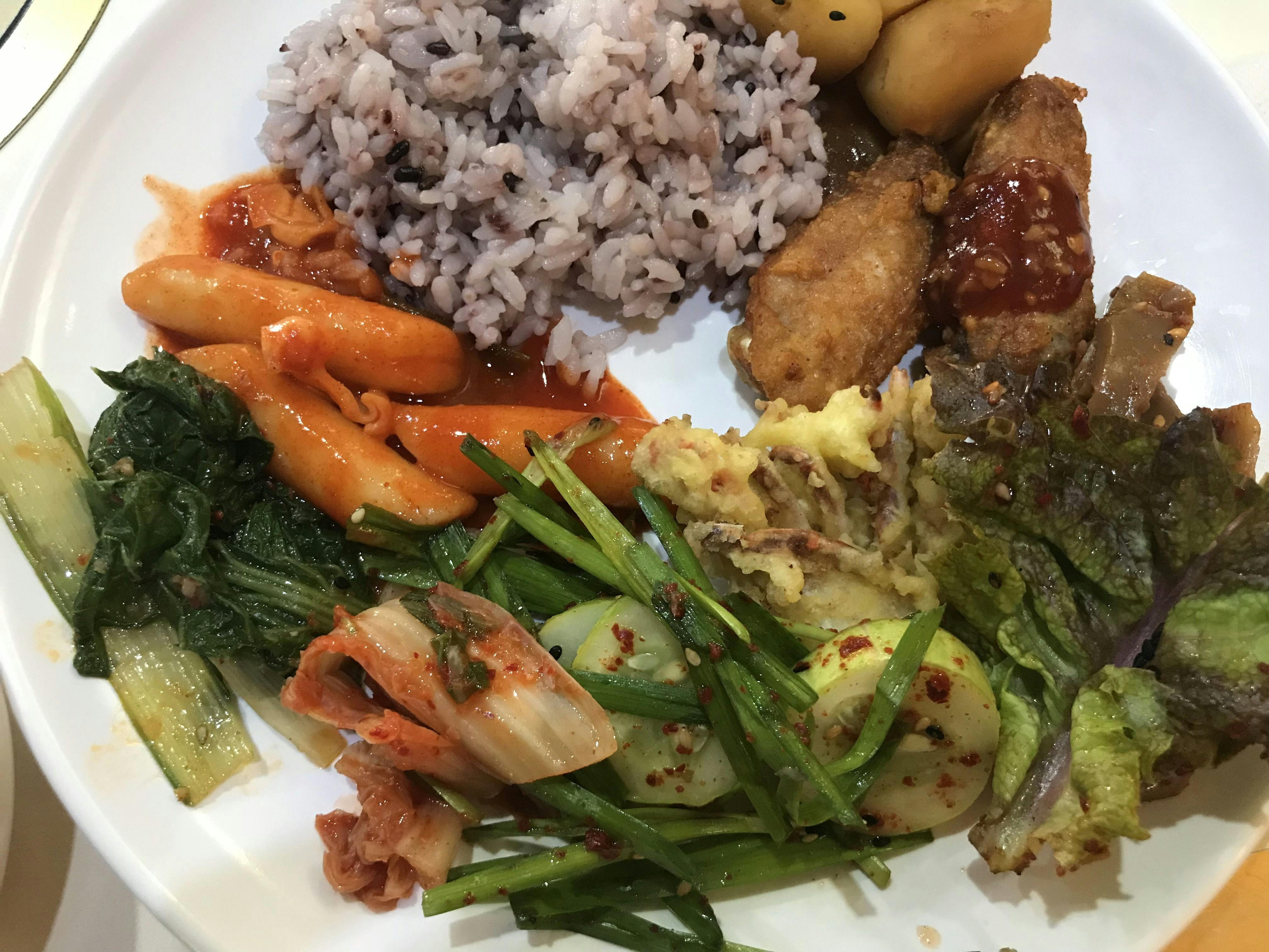 Korean bento box with rice, fried chicken, dumplings, seasoned vegetables, and miso soup