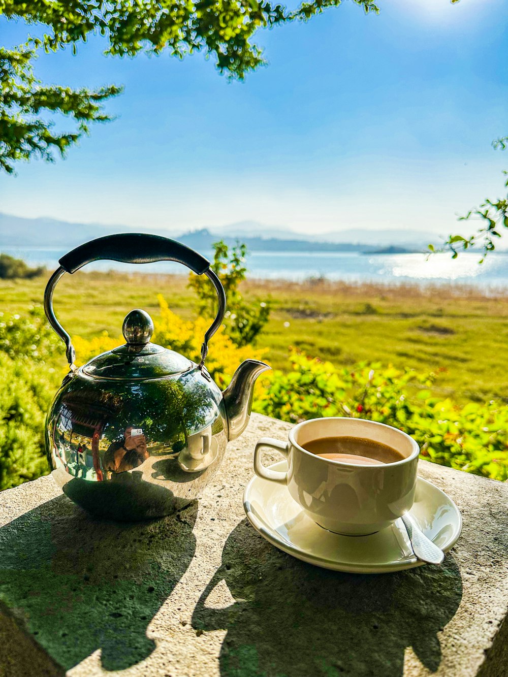 a cup of coffee and a tea kettle on a table