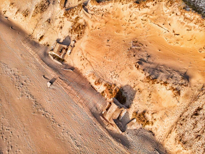 Scientists studying coastal erosion patterns on a sandy shoreline with measuring instruments.