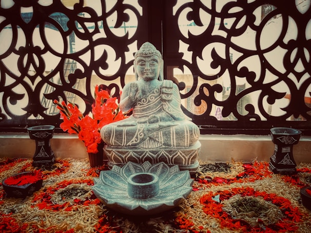 A close-up of a traditional Buddhist statue adorned with flowers.