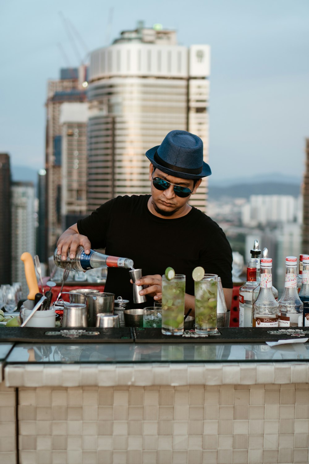 a man in a hat and sunglasses making a drink