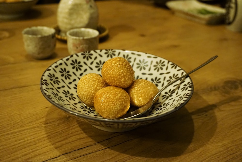 a bowl filled with small yellow balls on top of a wooden table