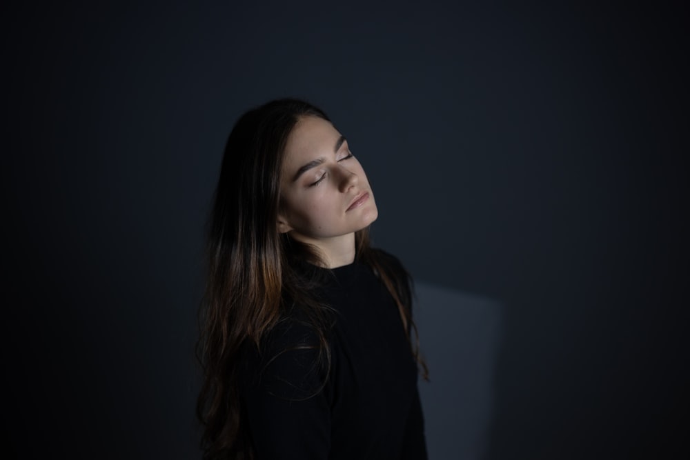 a woman with her eyes closed in a dark room