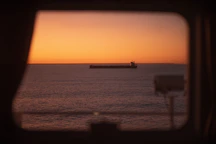 a view of a large cargo ship in the ocean at sunset