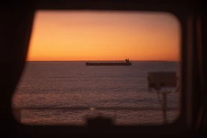 a view of a large cargo ship in the ocean at sunset