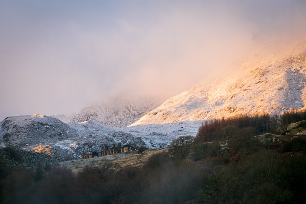 a snow covered mountain with a house in the foreground