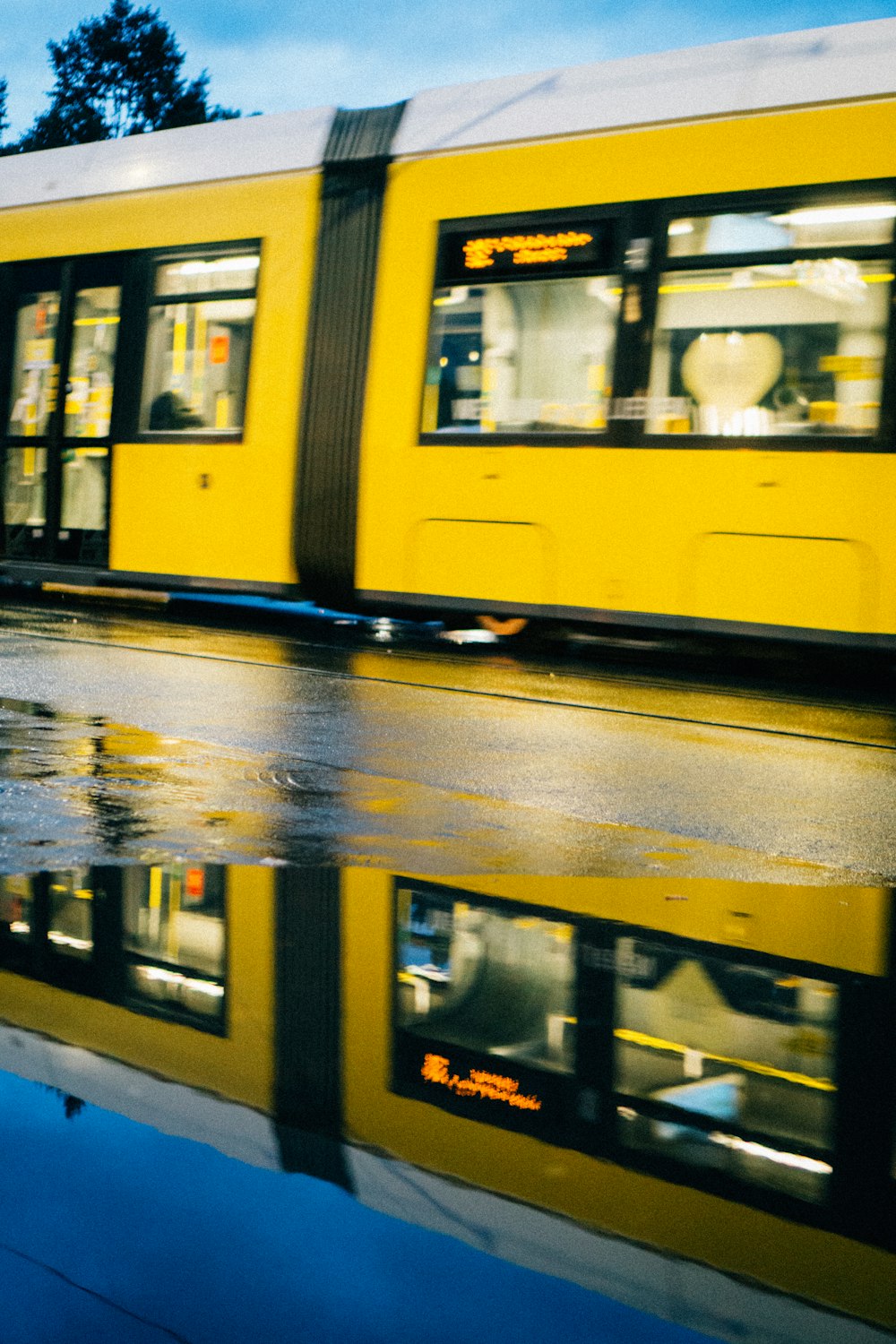 um trem amarelo viajando pelos trilhos do trem ao lado de uma poça