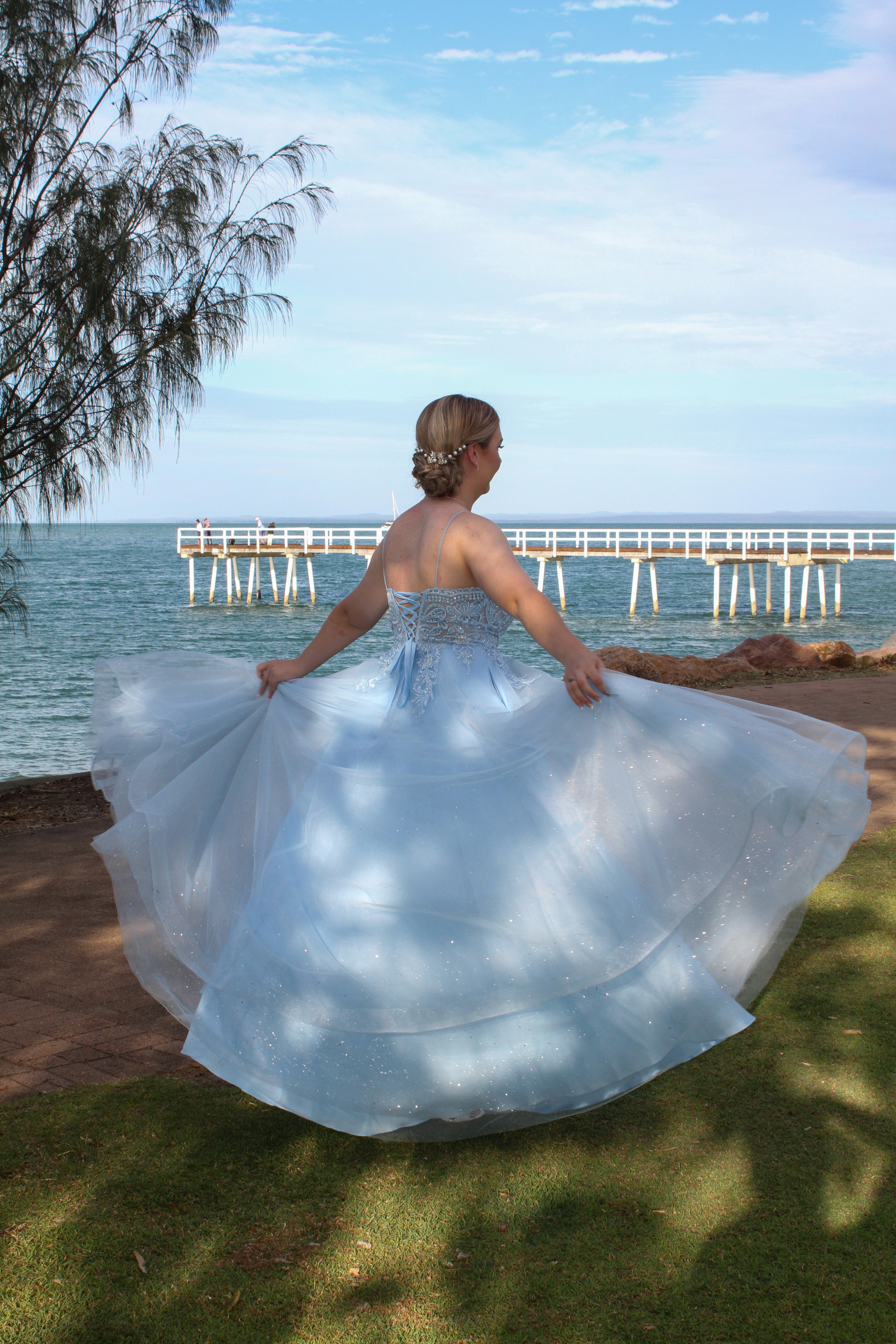 a woman in a blue and white dress is walking by the water