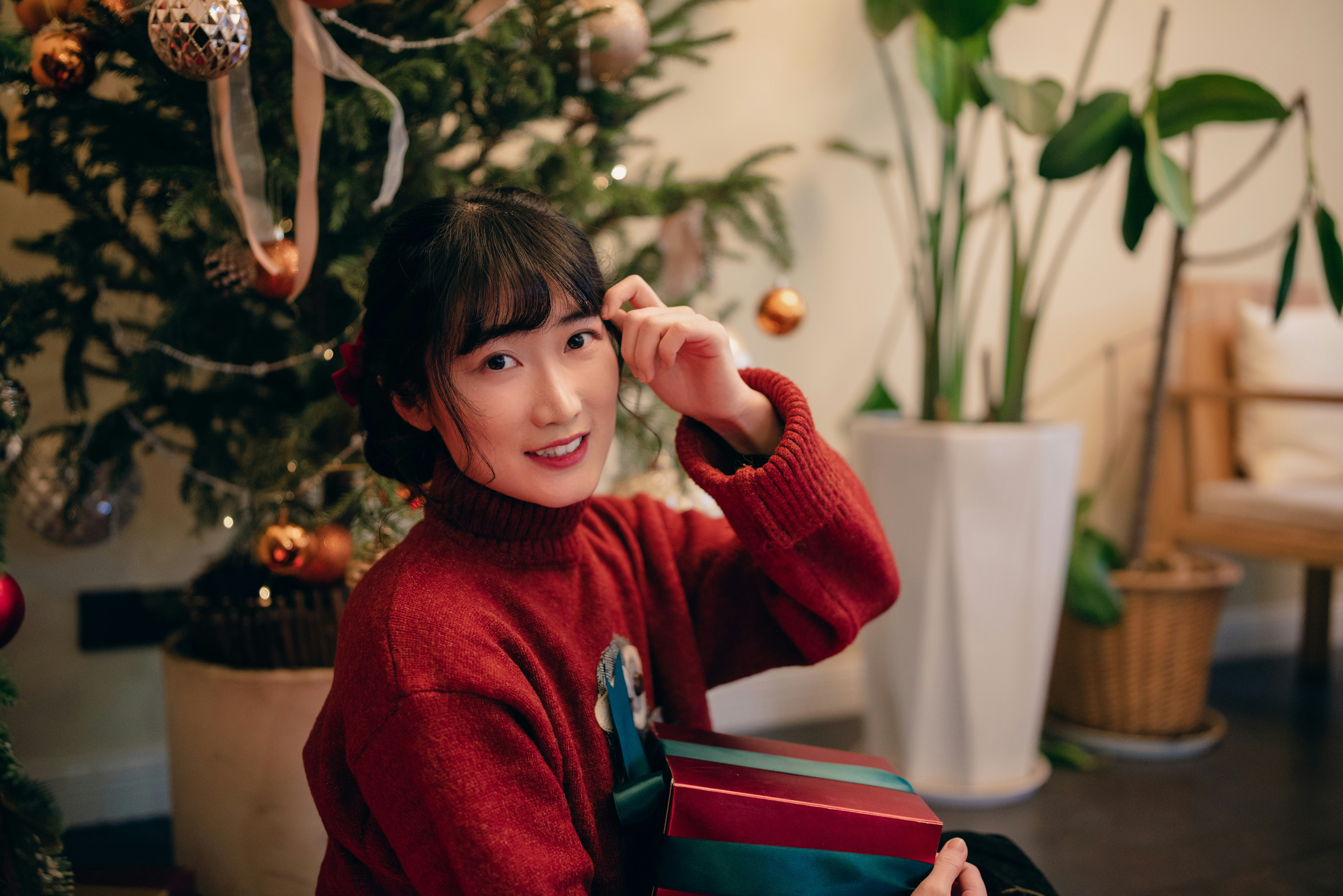 a woman in a red sweater is holding a present