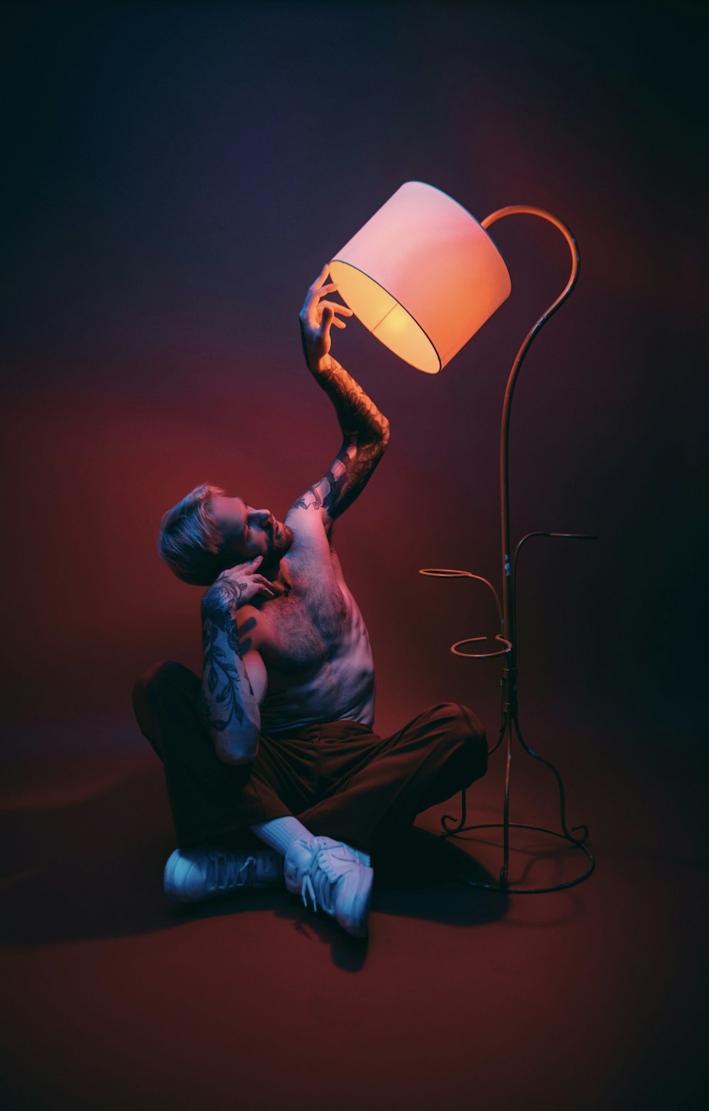 a man sitting on the floor next to a lamp