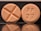 Two round tablets are displayed against a reflective black surface. One tablet features an engraved cross, while the other is marked with 'RP 27'. Both tablets have a consistent light orange color.