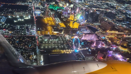 Aerial night view of Balneário Camboriú with glowing neon city lights and the FG Big Wheel illuminated.