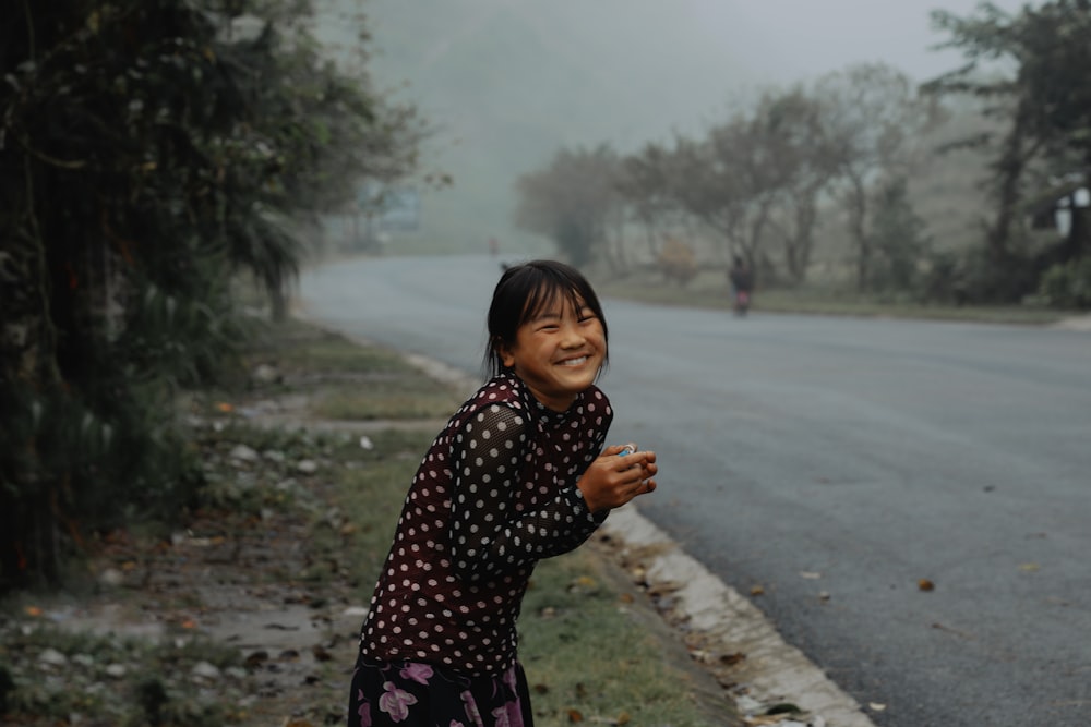 a young girl standing on the side of a road