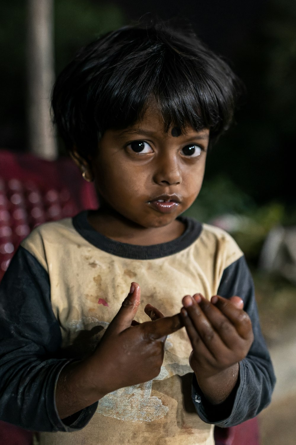 a young boy standing in front of a red chair