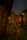 A person in traditional attire walks through the ancient stone corridor of a temple, illuminated by warm lights. The intricate architecture and carvings of the temple walls line the path, leading towards a towering gopuram under the evening sky.