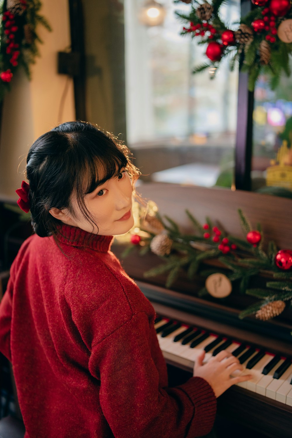 a woman in a red sweater playing a piano