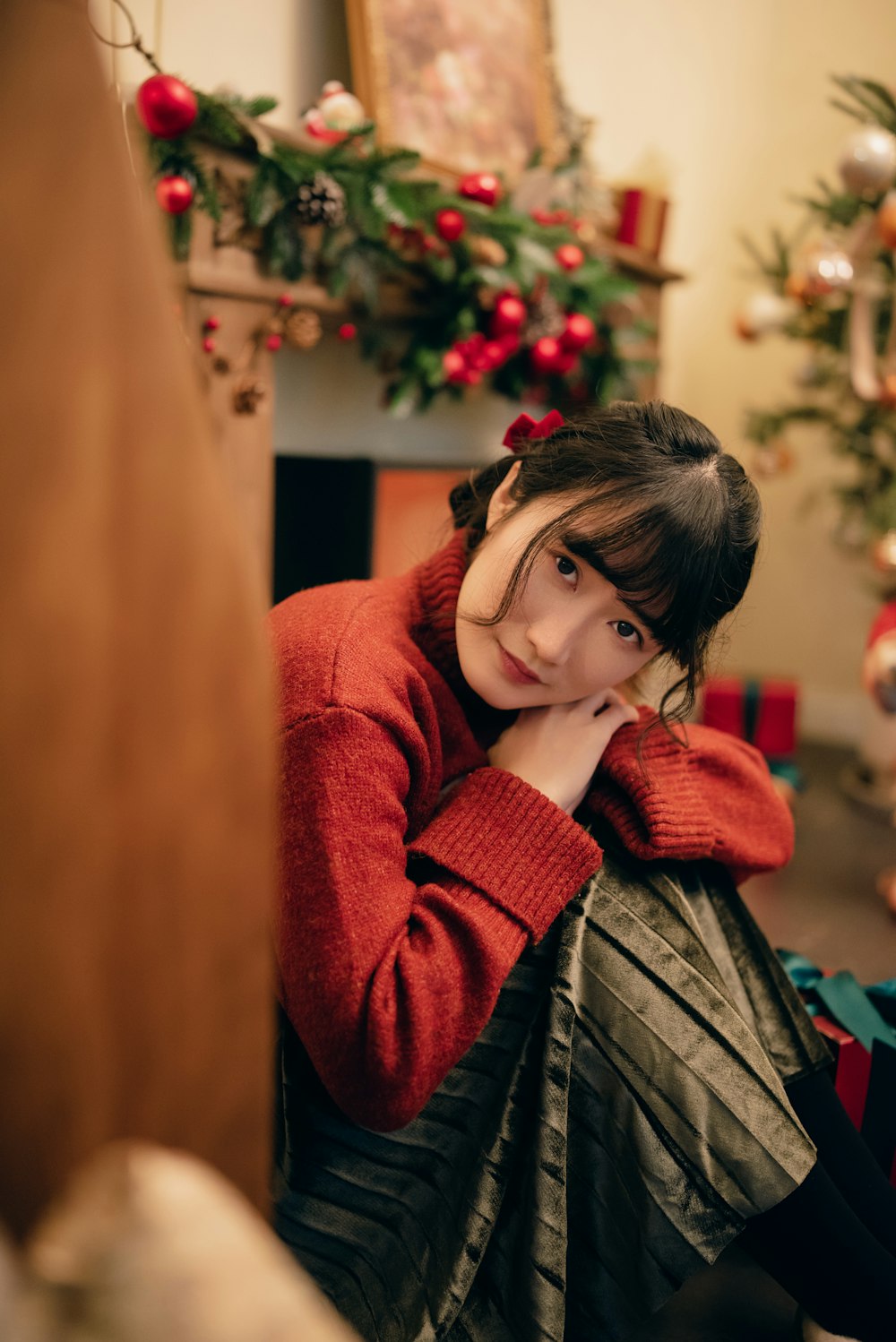 a woman sitting on the floor in front of a christmas tree