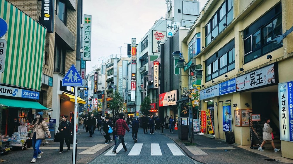 a group of people walking down a street next to tall buildings