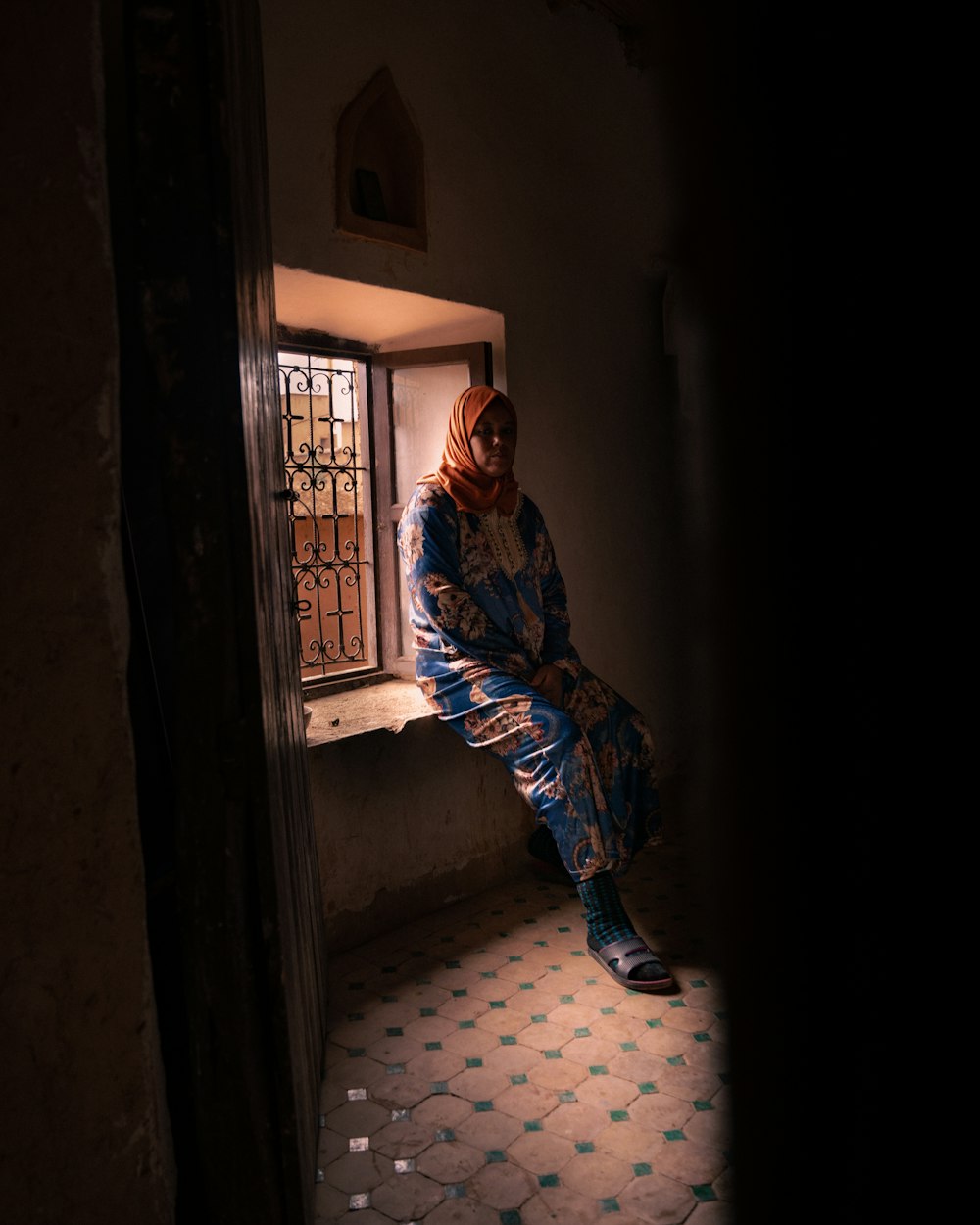 a woman sitting on a window sill in a dark room