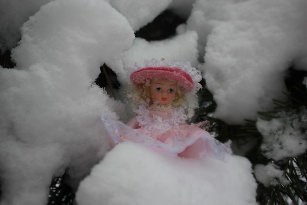Une petite poupée est assise dans la neige