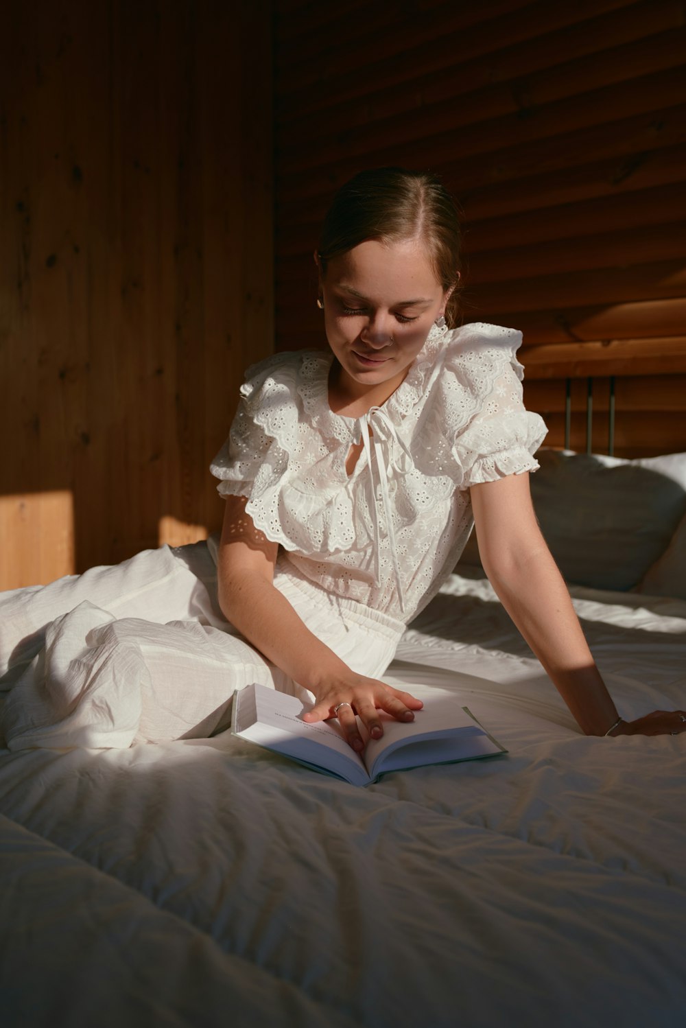 a woman sitting on a bed reading a book