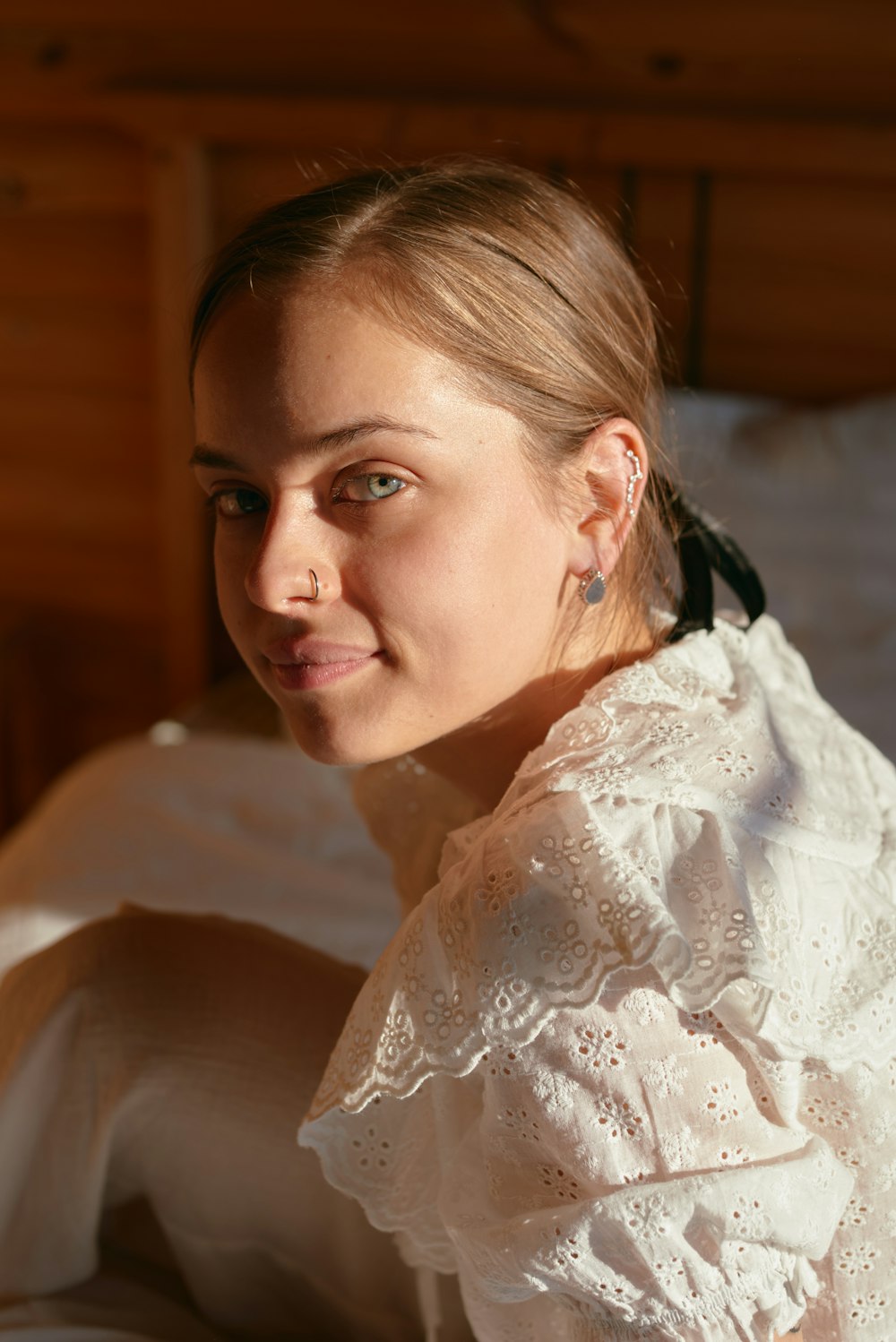 a woman sitting on a bed in a white dress