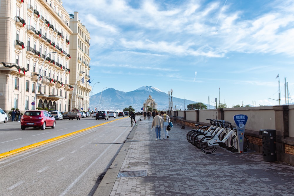 a group of people walking down a street next to parked bikes