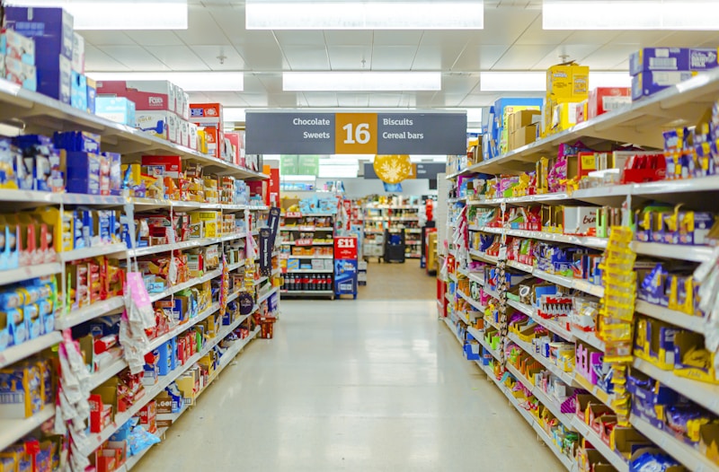 Hand reaching toward juice cartons in open refrigeration
