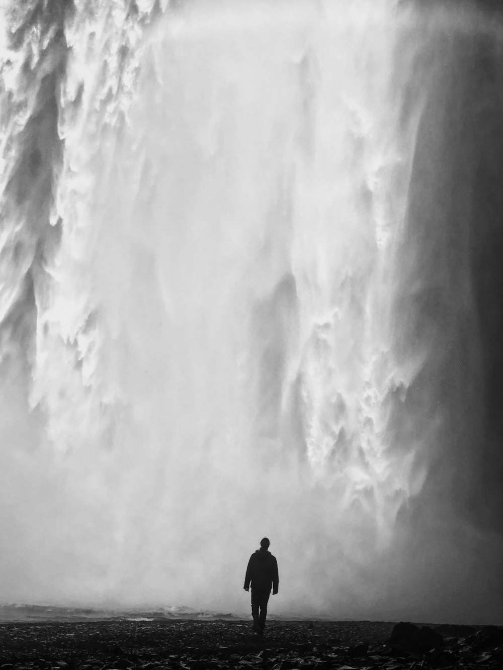 a man standing in front of a huge waterfall