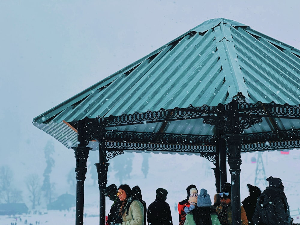 a group of people standing around a gazebo in the snow