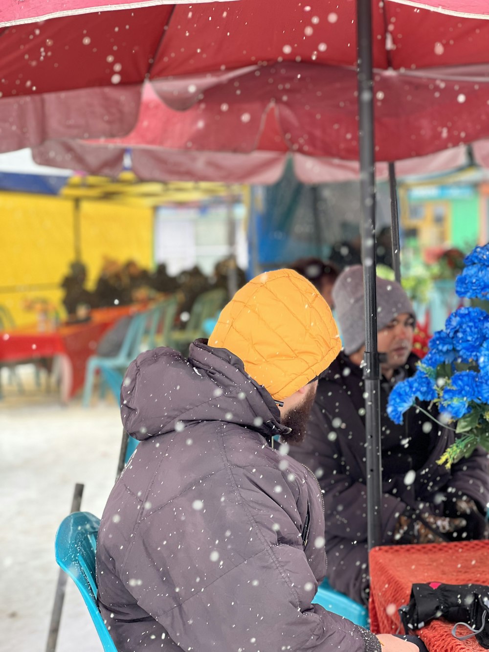 a person sitting in a chair under a red umbrella