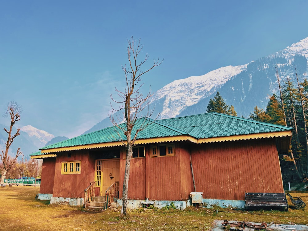 a red building with a green roof and a mountain in the background