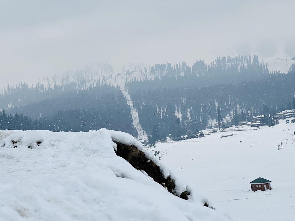 a snow covered hill with a small cabin in the distance