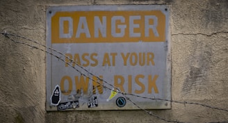 a sign on a wall that says danger pass at your own risk