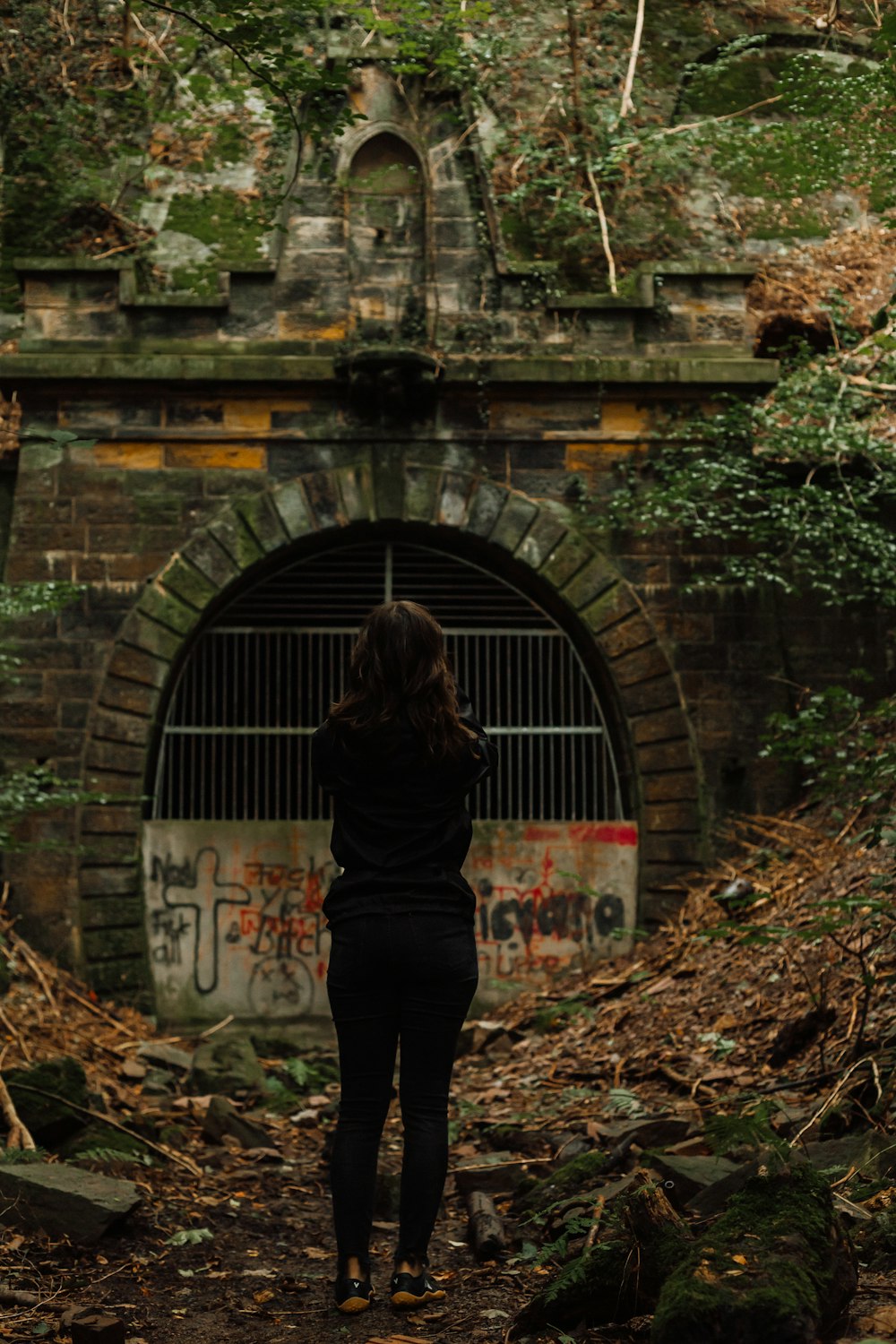 a woman standing in front of a brick tunnel