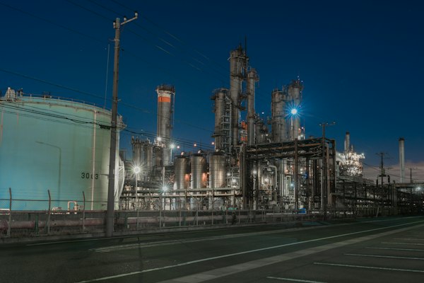 Planta de proceso con tuberías iluminada durante la noche, escenario del marketing para la industria química