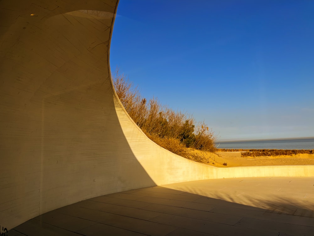 a curved concrete wall next to a body of water