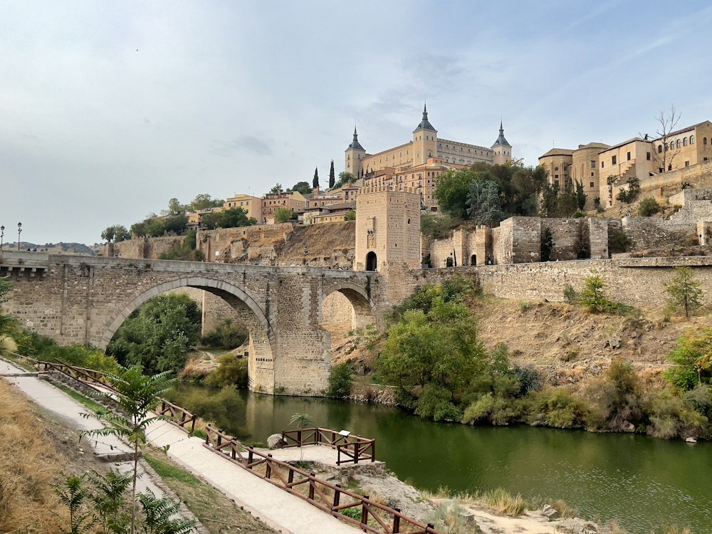 A stone bridge leading toward the fortified hilltop city of Toledo, Spain