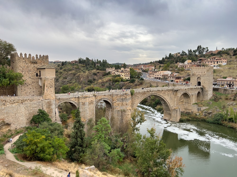 a stone bridge over a river in a city