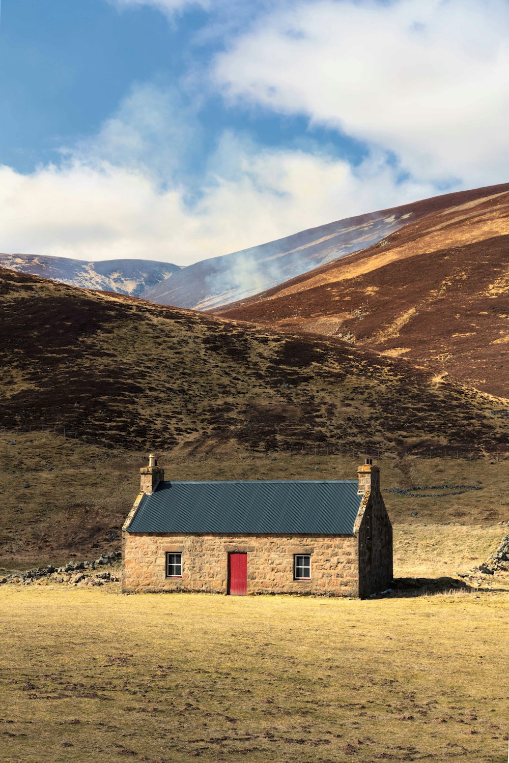 a small house in a field with mountains in the background