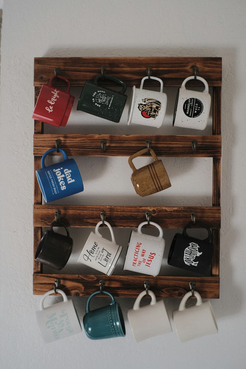 Un estante de madera con tazas de café colgando de él