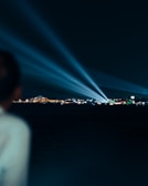 Powerful searchlight casting a bold beam over a nighttime cityscape in Massachusetts.
