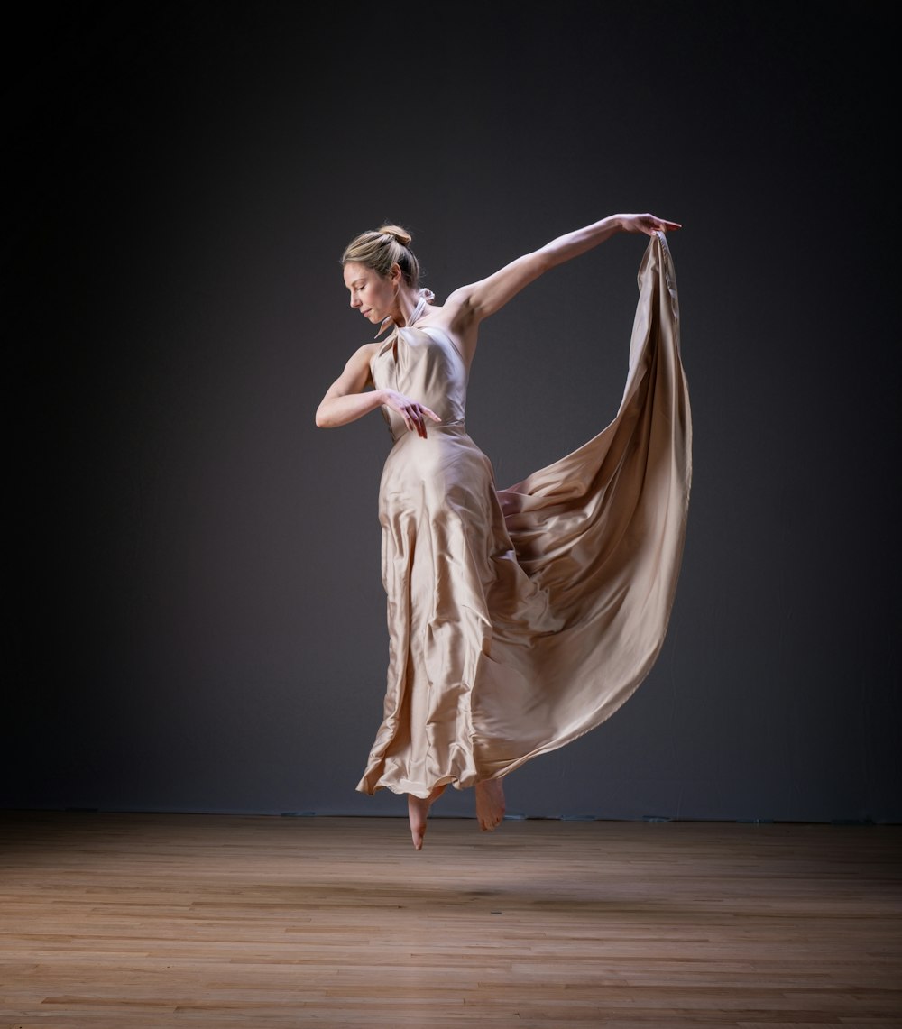a woman in a dress is dancing on a wooden floor