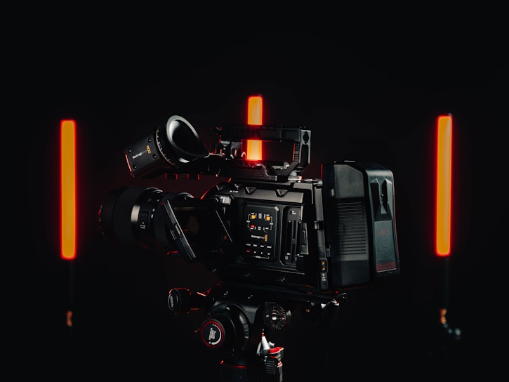 High-resolution 4K video camera setup capturing a commercial shoot in a dark studio with dramatic lighting.