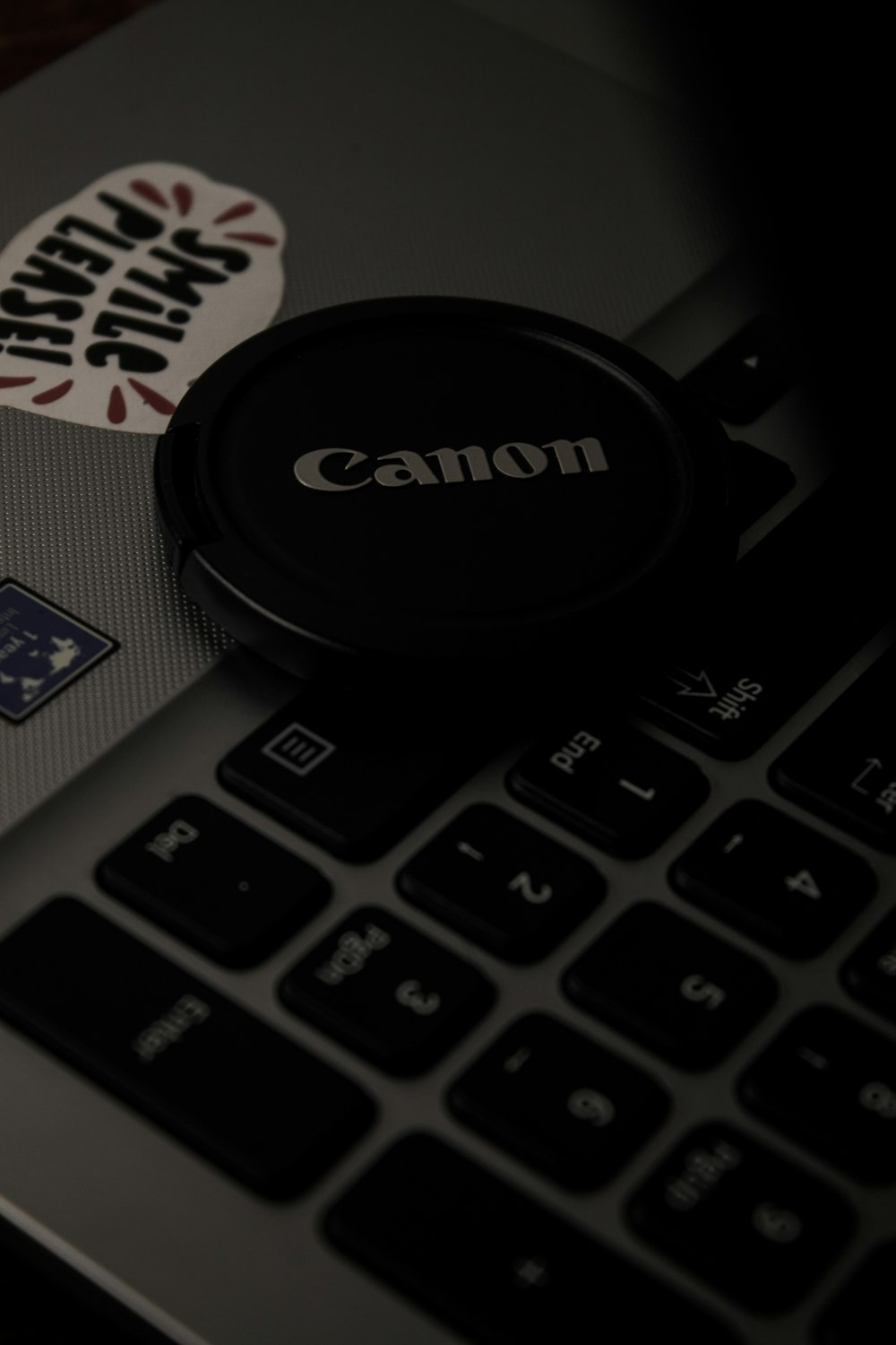 a close up of a laptop keyboard with a canon sticker on it