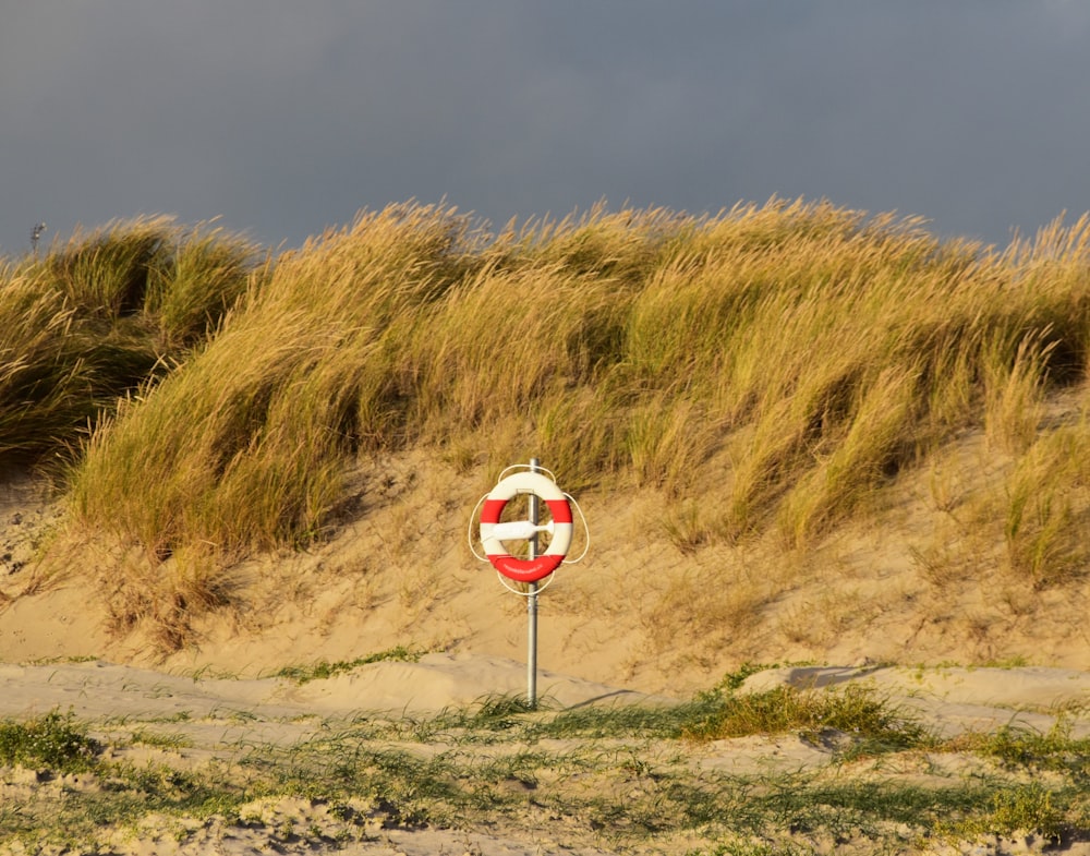 um sinal vermelho e branco sentado no topo de uma praia de areia