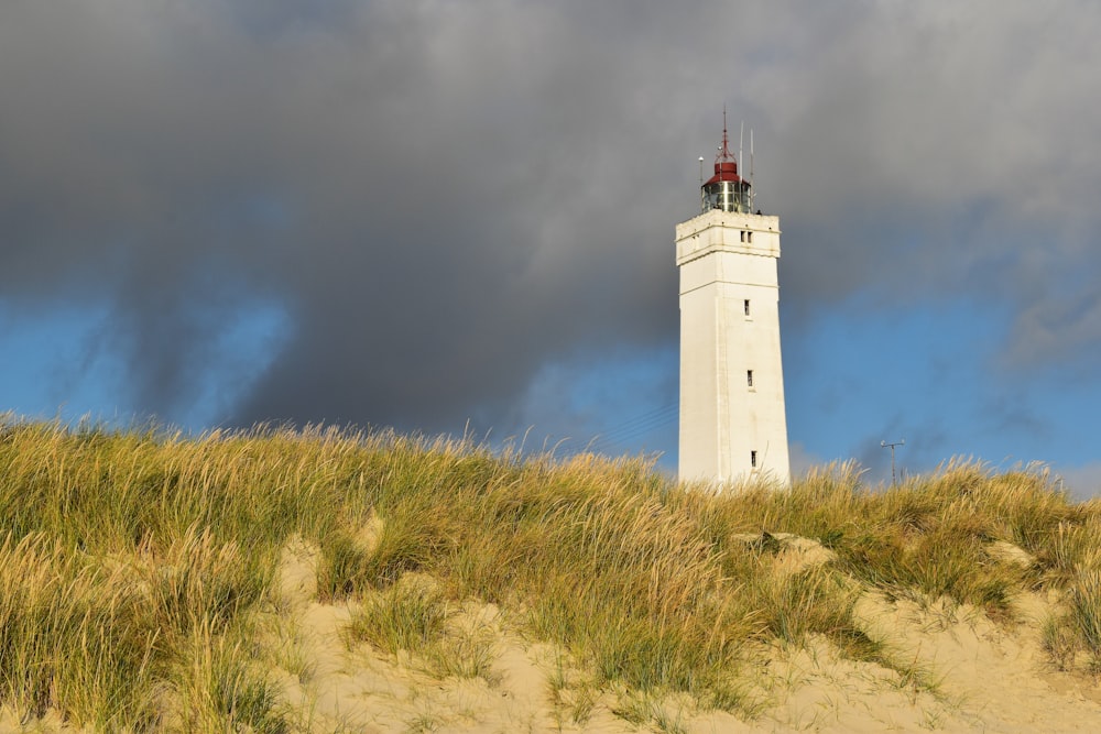 a tall white tower sitting on top of a sandy hill
