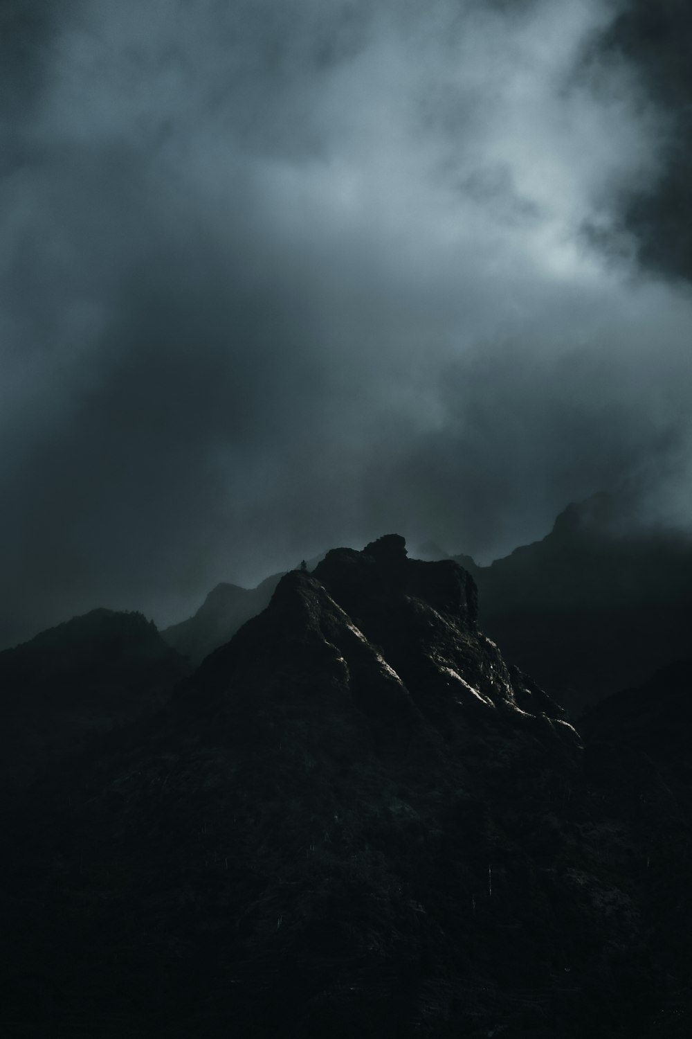 Ein Schwarz-Weiß-Foto eines Berges unter bewölktem Himmel