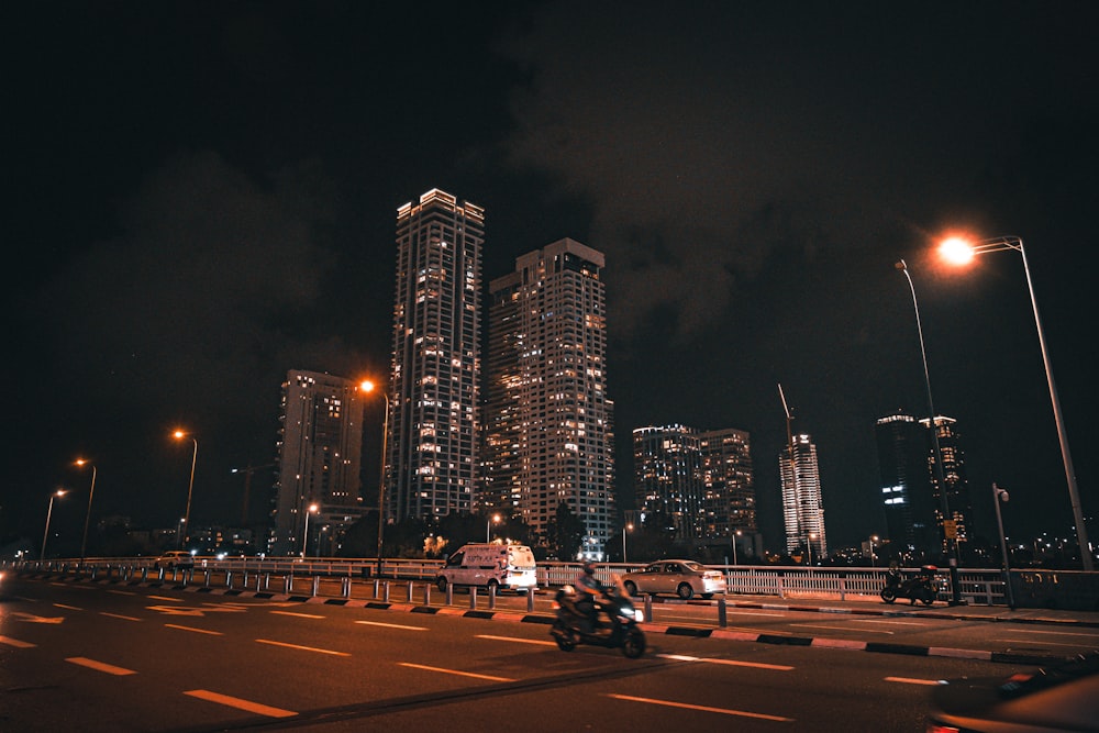 a motorcycle driving down a street next to tall buildings