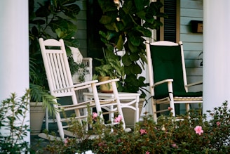 a couple of white rocking chairs sitting on top of a porch